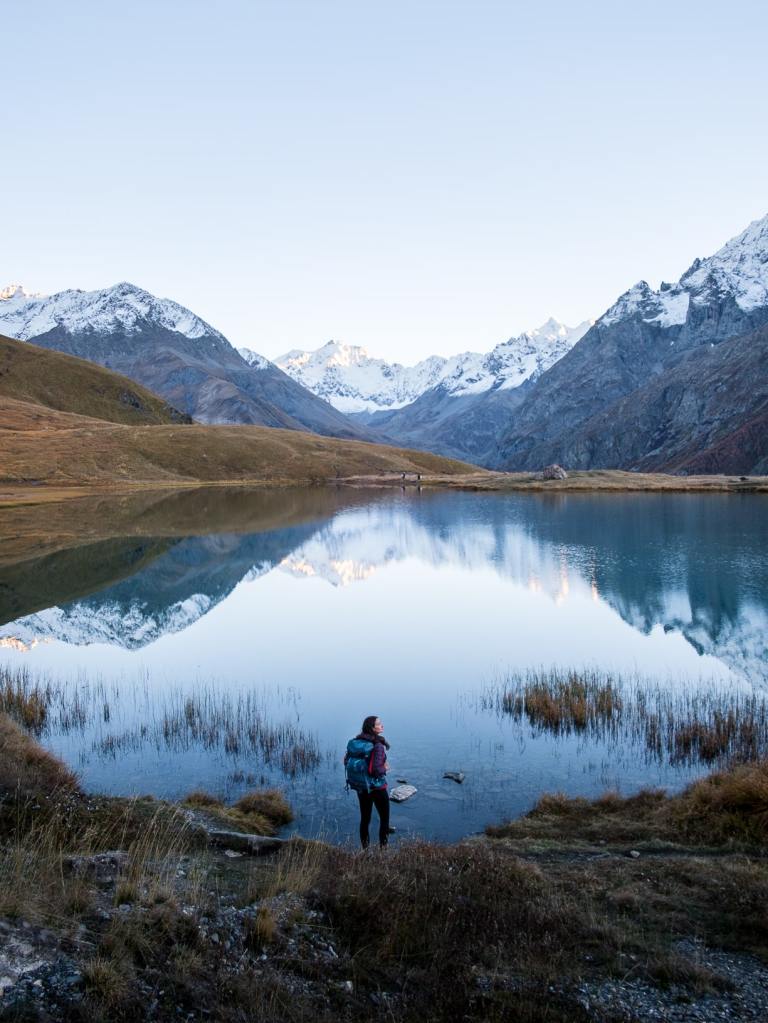 Lumière dorée sur le lac du Pontet et les glaciers des Écrins avec randonneuse devant le paysage